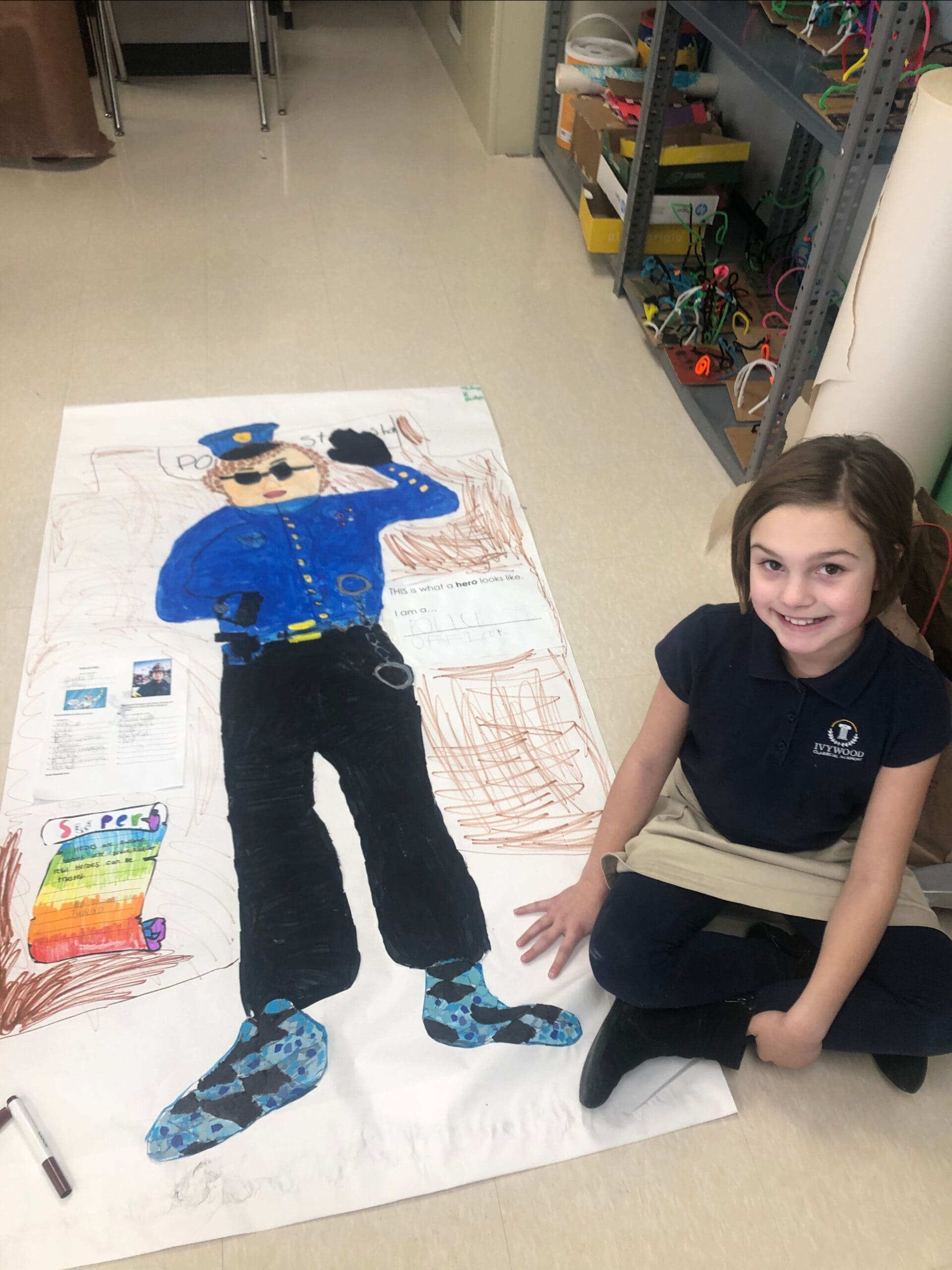 Ivywood student sitting next to her life size drawing of a police officer