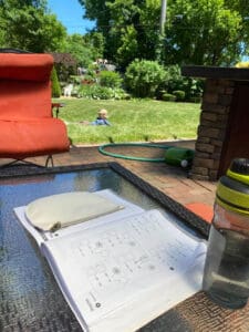 Math book on table, student laying in the grass